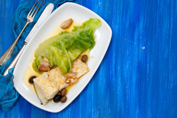 boiled cod fish with olive oil and vegetables on white plate