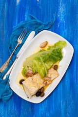 boiled cod fish with olive oil and vegetables on white plate