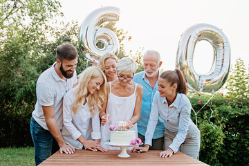 Family celebrating a  60th birthday, with balloons and cake, happy, cheering 