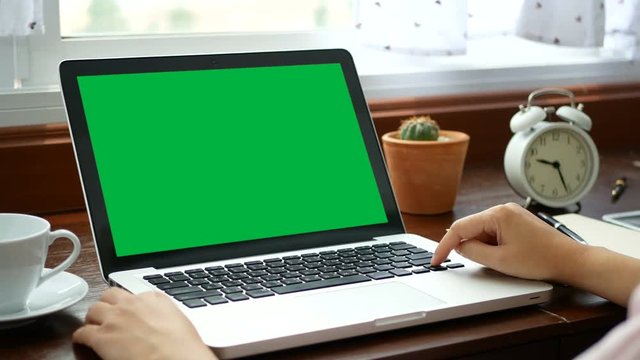 4K. close-up woman working at home with notebook laptop, using finger with keyboard and touchpad for slide. computer laptop with blank green screen chroma key.