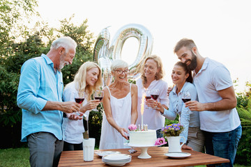 Family celebrating a  60th birthday, with balloons and cake, happy, cheering 
