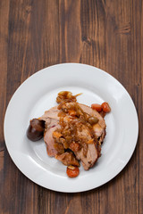 baked turkey leg with vegetables, smoked sausage and herbs on white dish