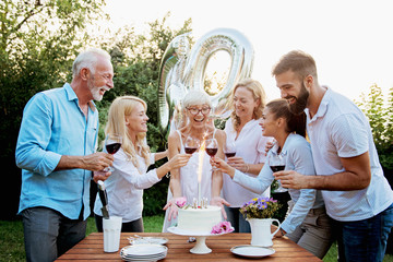 Family celebrating a 60th birthday, with balloons and cake, happy, cheering