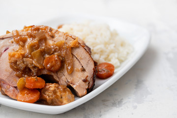 baked turkey leg with vegetables, smoked sausage, herbs and boiled rice on white dish