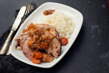 baked turkey leg with vegetables, smoked sausage, herbs and boiled rice on white dish