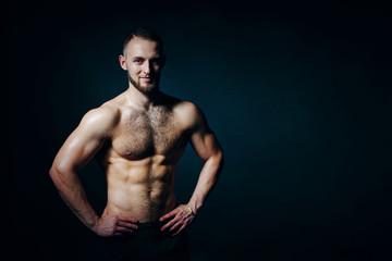Fototapeta na wymiar Low key portrait of muscular shirtless man at dark background