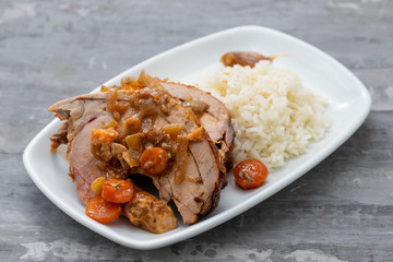 baked turkey leg with vegetables, smoked sausage, herbs and boiled rice on white dish