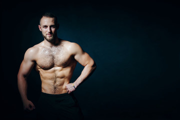 Fototapeta premium Low key portrait of muscular shirtless man at dark background