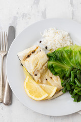 boiled cod fish with rice and vegetables on white plate