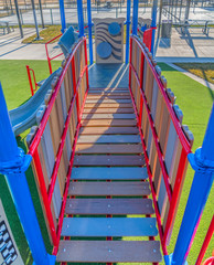 Playground equipment with a bridge and slide against vibrant green lawn