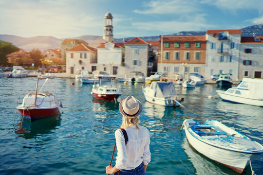 Tourism concept. Young traveling woman enjoying the view of Kastel Castle walking near the sea on Croatian coast.