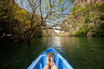 Kayaking through river in Matka canyon, Macedonia. Woman legs in the blue kayak