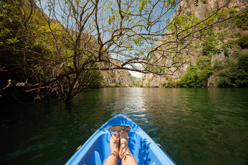 Fototapeta premium Kayaking through river in Matka canyon, Macedonia. Woman legs in the blue kayak