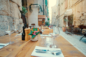 Outdoor restaurant summer terrace. Old vintage cafe with wooden table in europian old town.