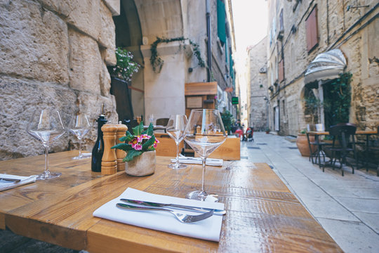 Fototapeta Outdoor restaurant summer terrace. Old vintage cafe with wooden table in europian old town.