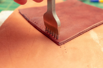 Punching holes in a leather wallet with line piercer diamond shape puncher tool before stitching...