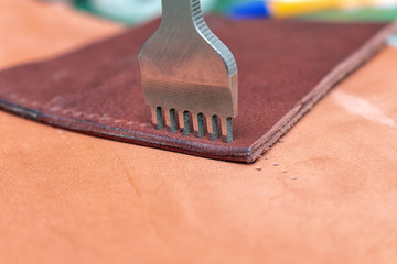 Punching holes in a leather wallet with line piercer diamond shape puncher tool before stitching...