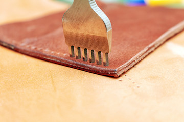 Punching holes in a leather wallet with line piercer diamond shape puncher tool before stitching...