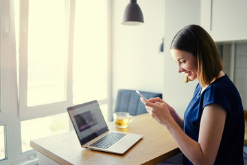 Working at home. Freelance concept. Business and technology. Pretty young woman using smartphone at home.