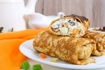 Delicious delicate pancakes with cottage cheese and raisins on a white wooden background. Healthy breakfast.
