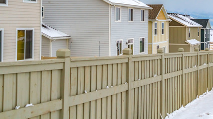 Clear Panorama Exterior of homes inside a wooden fence against a snowy landscape in winter