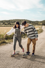 Millennial young couple having fun with a skateboard