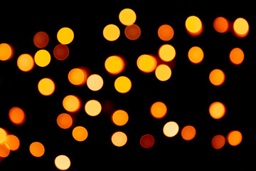 Holiday glowing gold backdrop. defocused and blurred many round yellow light on Christmas black background
