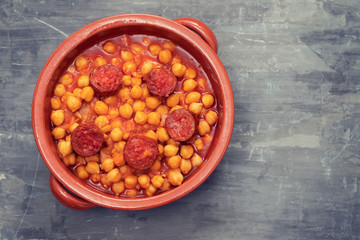 chick pea with smoked sausage chorizo  in small brown ceramic dish