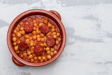 chick pea with smoked sausage chorizo  in small brown ceramic dish
