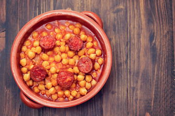 chick pea with smoked sausage chorizo  in small brown ceramic dish
