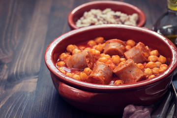 spanish sausage with chick-pea in small brown ceramic dish
