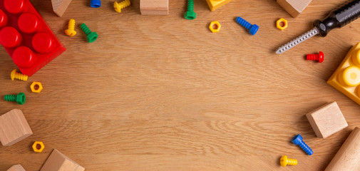 Kids toys frame background with toy tools, blocks and cubes on wooden table. Top view