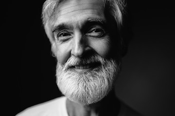 Close up studio portrait of handsome senior man with gray beard.