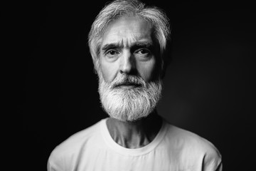 Studio portrait of frowning senior man with gray beard.
