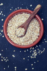 dry oats with spoon in ceramic bowl