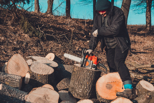 A young woman launches a chainsaw for cutting wood in the countryside - Powered by Adobe