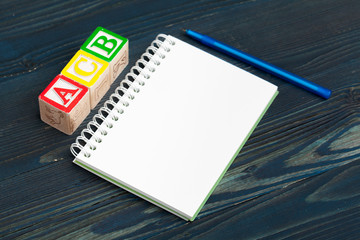Notepad on wooden table and wood alphabet blocks