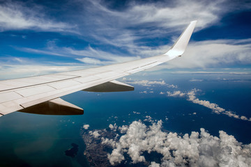Obraz premium Wing of airplane in cloudy sky