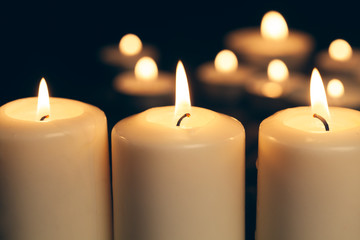 candles burning in darkness over black background. commemoration concept.