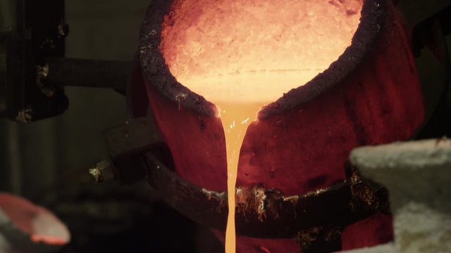 hot bronze being poured into molds in foundry
