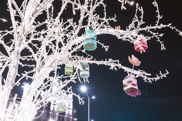 vintage birdhouse and other decorations with lamps on a big tree, city holiday decoration concept