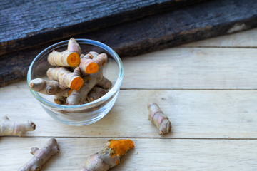 Stack of cut fresh turmeric on wood background, herb concept, traditional asian spice