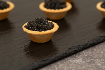 Tartlets with black caviar close up. Gourmet food close up, appetizer. Delicatessen. Gourmet food. Texture of caviar. Seafood. 