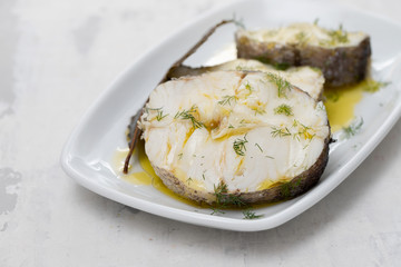 boiled fish with olive oil  and bay leaf in white dish