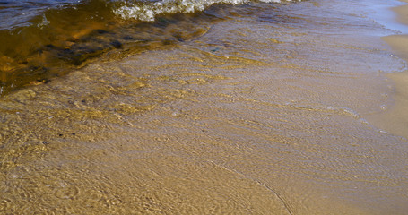 Clear waters of Rybinsk reservoir. Rolling waves on the beach sand. Summer seascape. Close up view. Yaroslavl region, Russia