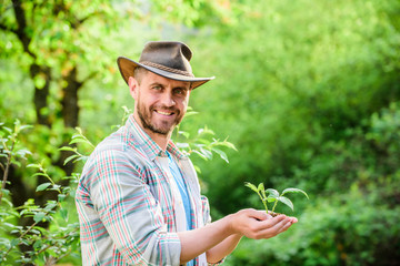Eco farm worker. Earth day. successful farmer hold plant in ground in hands. farming and agriculture cultivation. Gardening. happy earth day. Eco living. muscular ranch man in cowboy hat care plants