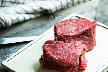 Rinderfilet vom Simmentaler Rind, roh afu einer Platte mit Messer und Geschirrtuch