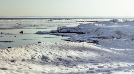 Snow pile, hill. Large snow drift isolated on a blue sky background,  outdoor view of ice blocks at frozen finland lake in winter