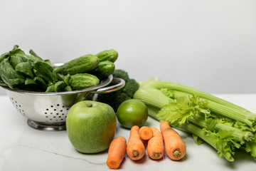 sweet carrots near ripe apple and green vegetables on grey