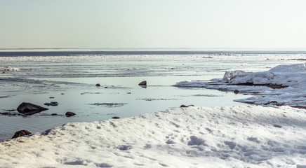 Snow pile, hill. Large snow drift isolated on a blue sky background,  outdoor view of ice blocks at frozen finland lake in winter